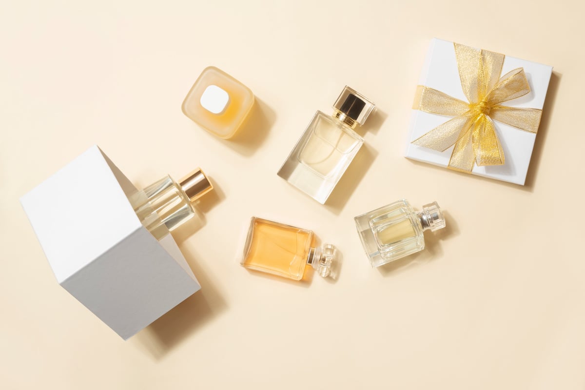 Many perfume bottles and gift box flat lay on light beige background