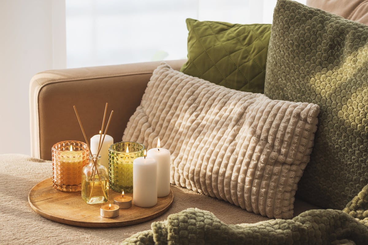 Candles and Reed Diffuser on Wooden Tray. Cozy Home Decor lifestyle with Cushions